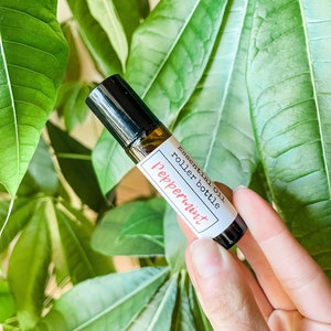 May include: A small glass roller bottle with a black cap and a white label that reads "essential oil roller bottle peppermint".