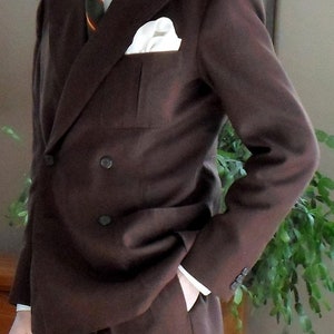 May include: A brown double-breasted suit jacket with a white pocket square and a striped tie.