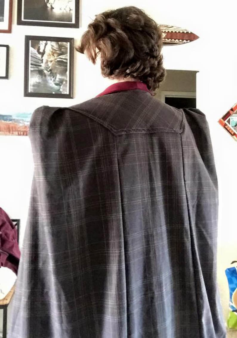 Op de afbeelding: Een geruite jas met een bordeauxrode kraag en opgeblazen schouders. De jas is gemaakt van een zachte, comfortabele stof en heeft een klassiek, tijdloos ontwerp.