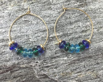 blue and green glass beads beaded on gold metal hoop earrings with gold metal bead accents