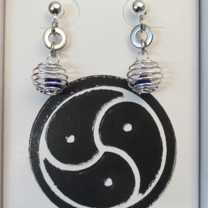 Puede incluir: Un par de pendientes de plata con una cuenta azul dentro de un dise&ntilde;o en forma de jaula. Los pendientes se muestran en una caja blanca con un s&iacute;mbolo negro.