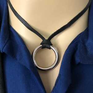 May include: A black leather necklace with a silver ring pendant.