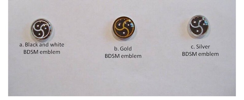May include: Three BDSM emblems in black and white, gold, and silver. Each emblem features a stylized triskelion design. The text below each emblem reads "Black and white BDSM emblem", "Gold BDSM emblem", and "Silver BDSM emblem".