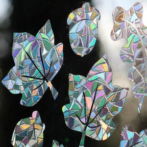 May include: A set of nine iridescent, stained glass-style leaf and acorn stickers. The stickers are in shades of blue, green, purple, and gold.