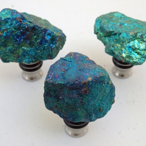 May include: Three blue and green gemstone bottle stoppers with a metallic silver base.