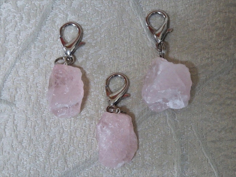 May include: Three pink rose quartz crystal keychains with silver metal clasps.