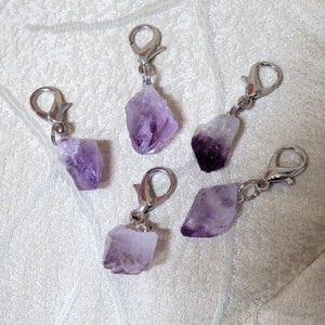 May include: Five amethyst crystal charms with silver lobster clasps. The amethyst crystals are various shapes and sizes.