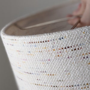 close up image of hand holding a custom lamp shade in handwoven Confetti fabric