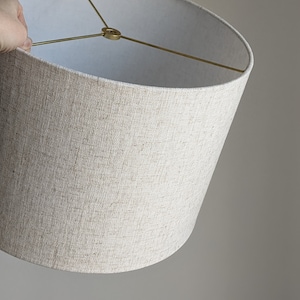 hand holding handmade lampshade in Calacatta Gold Flax fabric with brass hardware