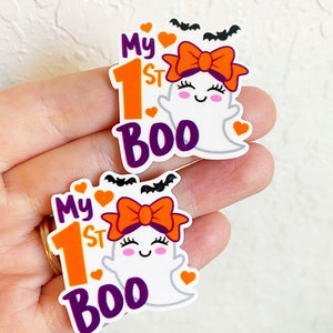 May include: Two white ghost-shaped stickers with orange and purple accents. The stickers feature a ghost with a bow, the number "1", and the text "My 1st Boo".