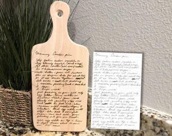 May include: A wooden cutting board with a handwritten recipe for "Grandma's Cranberry Pie" engraved on the surface. The recipe includes ingredients like cranberries, butter, sugar, and eggs.
