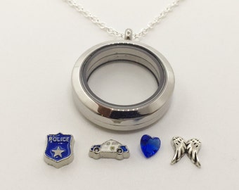 May include: A silver locket necklace with a silver chain. The locket has a clear glass insert. There are five charms: a silver police badge with a blue enamel star, a silver car charm, a blue heart charm, and two silver angel wings charms.
