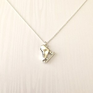 Puede incluir: Un collar de plata con un dije de plata en forma de patín de hielo. El dije es detallado y realista.