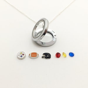 Może przedstawiać: Srebrny naszyjnik z zawieszką, kt&oacute;ra zawiera r&oacute;żne wisiorki, w tym piłkę nożną, logo Steelers, hełm i trzy kamienie szlachetne w kolorze czerwonym, ż&oacute;łtym i niebieskim.