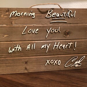 May include: Wooden sign with the words "Morning Beautiful", "Love you!" and "with all my heart!" written in white paint. The sign is signed "xoxo Carl".