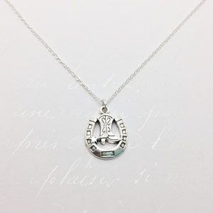 May include: A silver necklace with a horseshoe pendant featuring a cowboy boot and a star. The horseshoe is detailed with a textured design.