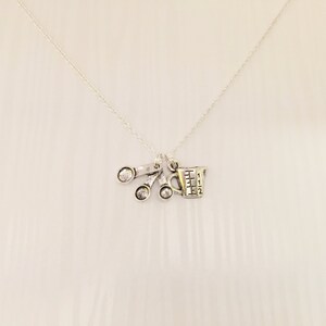 Puede incluir: Collar de plata con un dije de una taza medidora y tres cucharas medidoras. Los dijes est&aacute;n unidos a una cadena de plata.