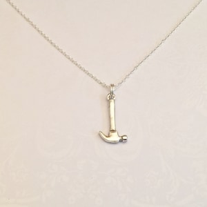 May include: A silver chain necklace with a silver hammer pendant.