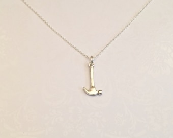 May include: A silver chain necklace with a silver hammer pendant.