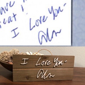 May include: A wooden sign with the words "I Love You" and a signature that says "Alan" in cursive. The sign is made of rustic wood and has a distressed look.