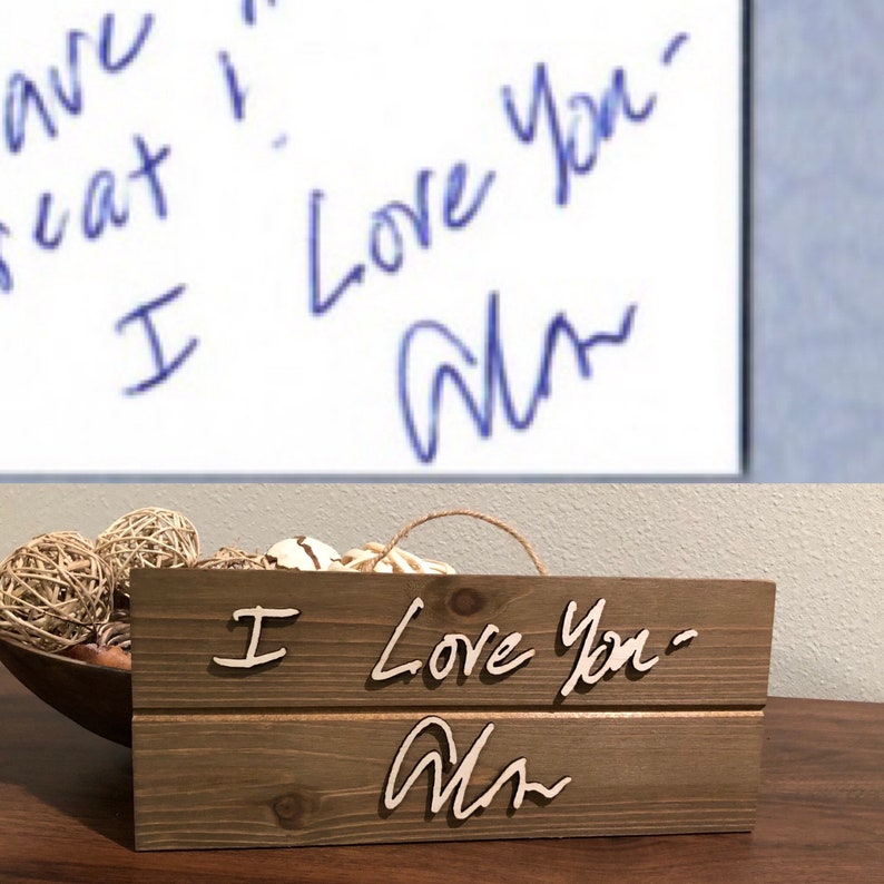 May include: A wooden sign with the words "I Love You" and a signature that says "Alan" in cursive. The sign is made of rustic wood and has a distressed look.