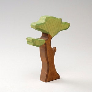 May include: A wooden toy tree with a brown trunk and green leaves. The tree is made of wood and has a simple, whimsical design.