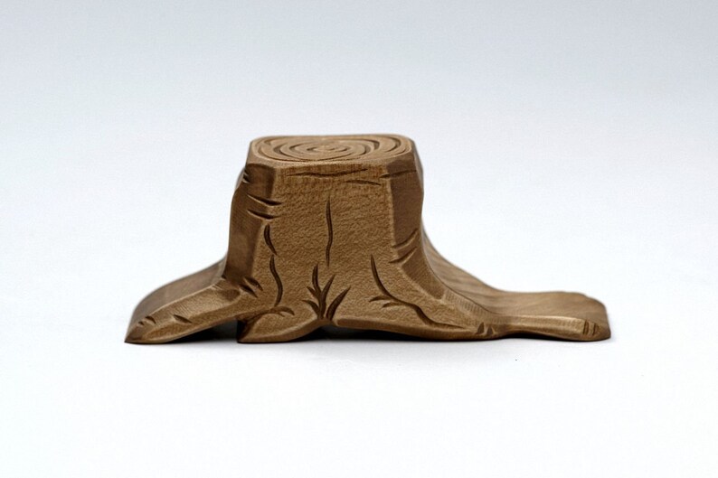 May include: A wooden tree stump with a carved, detailed design. The stump is light brown and has a circular top.