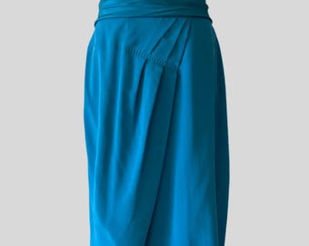 Peut inclure: Une jupe en soie bleu turquoise avec une large ceinture pliée. La jupe est mi-longue et a une silhouette fluide et drapée.