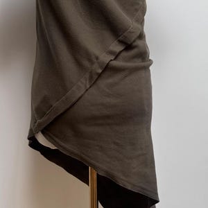 May include: A dark green asymmetrical t-shirt with a single seam detail on the front.