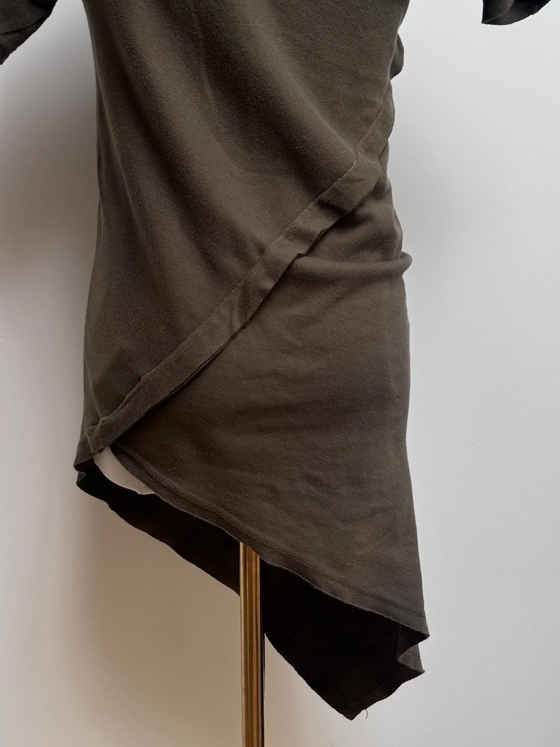 May include: A dark green asymmetrical t-shirt with a single seam detail on the front.