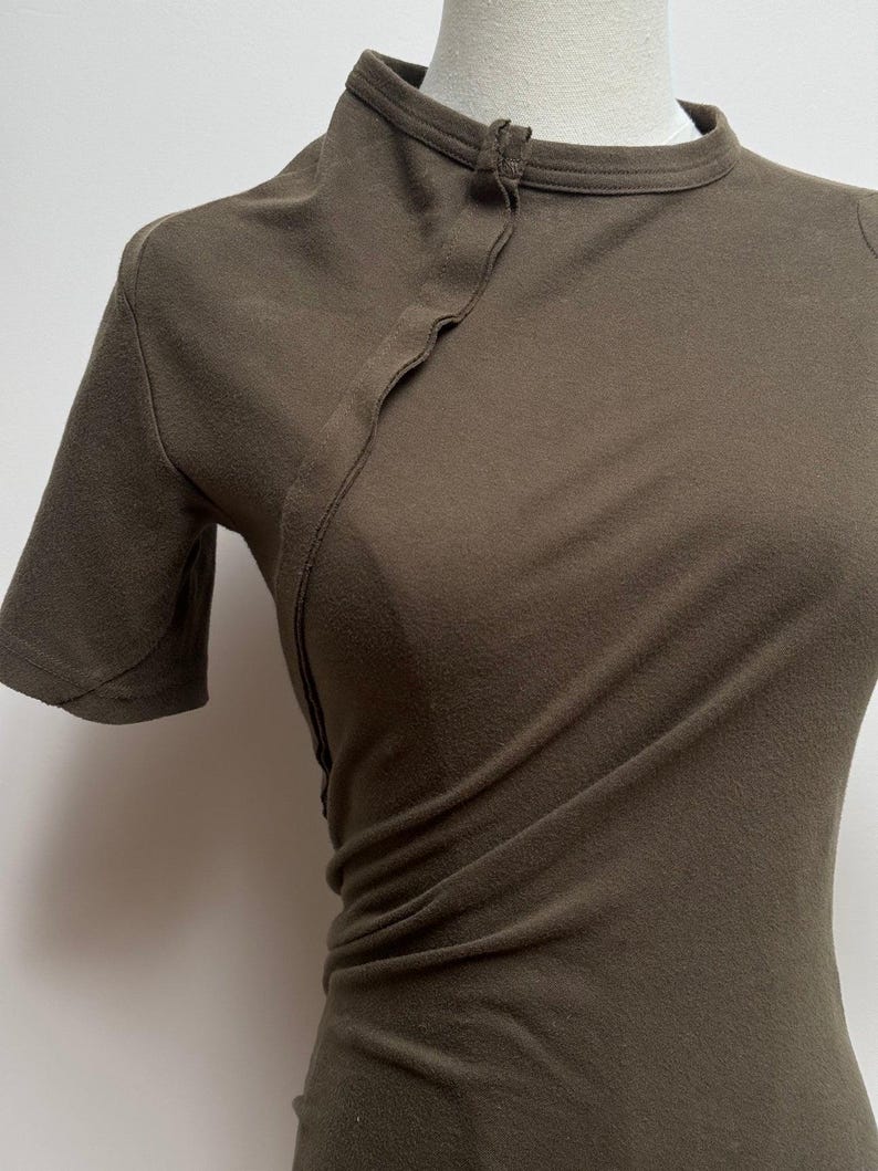 May include: A dark green short-sleeved shirt with a mandarin collar and a single button closure at the neckline.