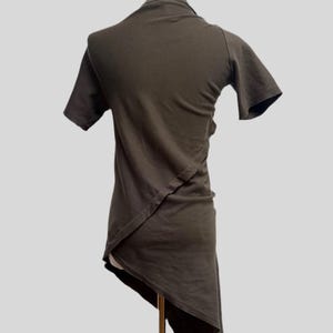 May include: A brown asymmetrical t-shirt with short sleeves. The shirt is made of a soft, comfortable fabric and has a unique design.