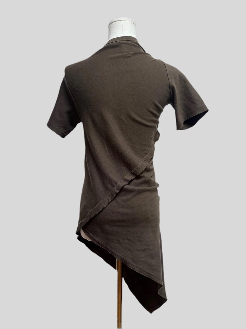 May include: A brown asymmetrical t-shirt with short sleeves. The shirt is made of a soft, comfortable fabric and has a unique design.