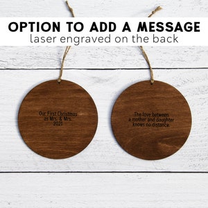 May include: Two round wooden ornaments with laser engraved messages. The first ornament says "Our First Christmas as Mrs. & Mrs. 2021". The second ornament says "The love between a mother and daughter knows no distance."