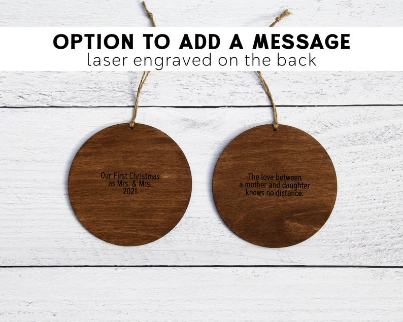 May include: Two round wooden ornaments with laser engraved messages. The first ornament says "Our First Christmas as Mrs. & Mrs. 2021". The second ornament says "The love between a mother and daughter knows no distance."