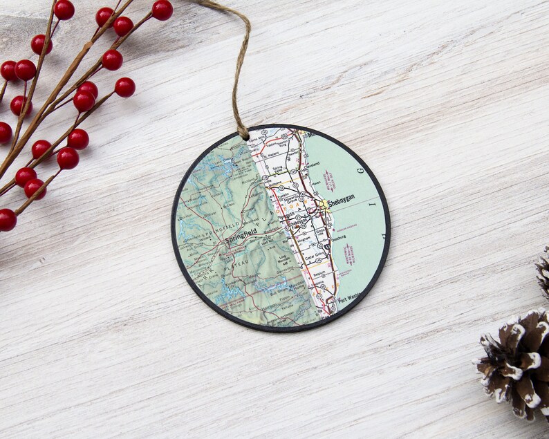 May include: A round, green and white map ornament with a black border. The map shows the area around Sheboygan, Wisconsin. The ornament has a string for hanging.