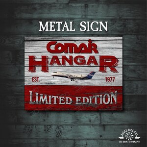 May include: Red and white metal sign with the text "ComAir Hangar Est. 1977 Limited Edition" and a small airplane image.