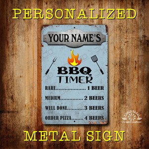 May include: A personalized metal sign with the text "YOUR NAME'S" above "BBQ TIMER". The sign has a light blue background with a flame graphic and grilling tools. The sign reads "RARE...1 BEER, MEDIUM...2 BEERS, WELL DONE...3 BEERS, ORDER PIZZA...4 BEERS".