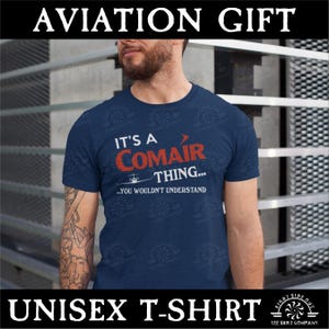 May include: Navy blue unisex t-shirt with the text "IT'S A COMAIR THING... YOU WOULDN'T UNDERSTAND" in white and red. The shirt also has a small airplane graphic. The top of the image reads "AVIATION GIFT".