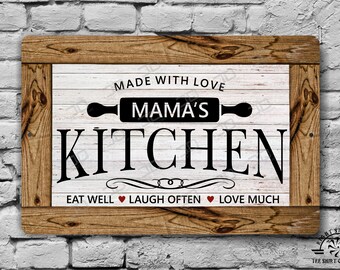 May include: Wooden framed sign with the text "MADE WITH LOVE MAMA'S KITCHEN" in black. The sign also includes the text "EAT WELL, LAUGH OFTEN, LOVE MUCH" with heart symbols. The background is white with a wood grain pattern.