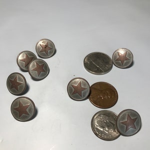 May include: A collection of silver-toned metal buttons with a red star design. The buttons are arranged on a white surface with two US coins.