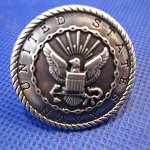 May include: A silver-toned metal pin with a rope-like border. The center features the United States Navy seal with an eagle, anchor, and the words "United States Navy".