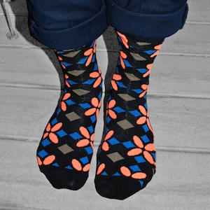 May include: A pair of black socks with a geometric pattern of orange flowers and blue diamonds.