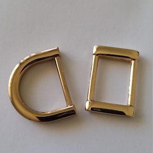 May include: Two gold-coloured metal rings, one D-shaped and one square, for attaching to a strap or chain.