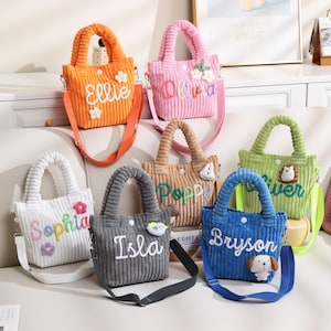 May include: A collection of corduroy tote bags in various colors, each personalized with a name in cursive lettering. The bags feature matching handles and adjustable shoulder straps. Some bags have floral or animal embellishments.