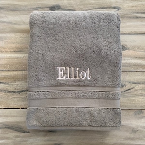 May include: A gray bath towel with the name "Elliot" embroidered in white.