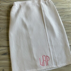 May include: White waffle weave bath wrap with a pink monogram of the letters "LRP" embroidered on the front.