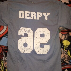 May include: A gray t-shirt with the word "DERPY" and the number "96" printed on the back in white.