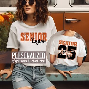 Pu&ograve; includere: Maglietta bianca con il testo "SENIOR Taylor" in lettere arancioni e nere. Il retro della maglietta ha il testo "SENIOR 25 Twenty" in lettere arancioni e nere.