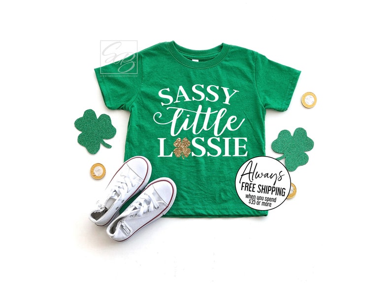 May include: Green t-shirt with white text that says "Sassy little Lossie" with a gold glitter shamrock.
